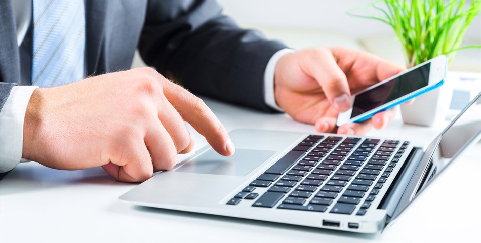 BankID tilbys både på mobil og laptop. For å benytte mobiløsningen må du ha et norsk telefonnummer og være registrert som bosatt i Norge. Bilde av mann med mobiltelefon og laptop.